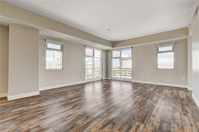 unfurnished room with dark wood-type flooring, plenty of natural light, and baseboards