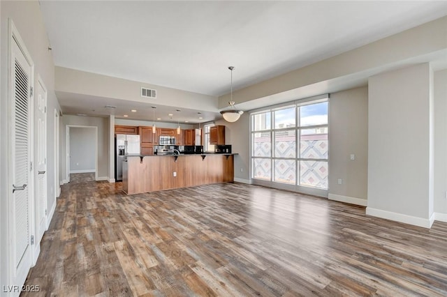 unfurnished living room featuring dark wood-type flooring and baseboards