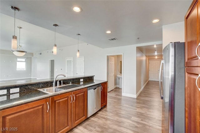 kitchen featuring stainless steel appliances, a sink, light wood finished floors, baseboards, and brown cabinets