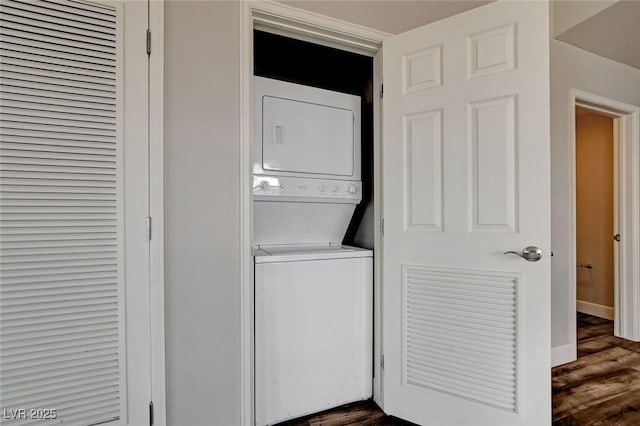 washroom with stacked washer / dryer, dark wood finished floors, and baseboards