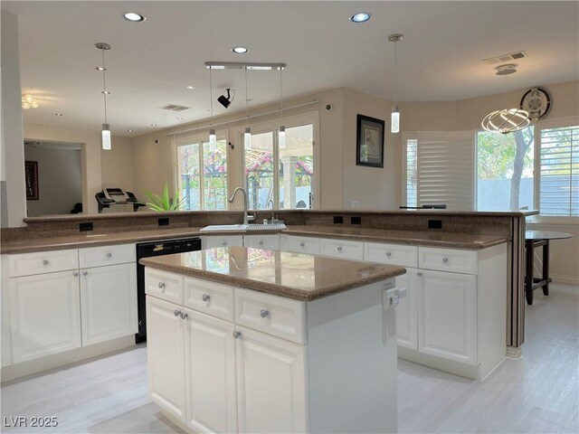 2451 Tour Edition Dr, Henderson, NV 89074 - kitchen featuring dishwasher, a center island, a sink, light wood-style floors, and dark stone countertops