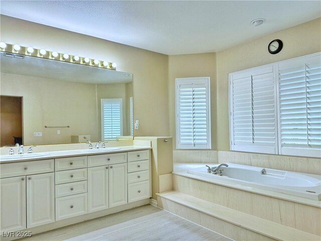 2451 Tour Edition Dr, Henderson, NV 89074 - full bath featuring healthy amount of natural light, a garden tub, double vanity, and wood finished floors