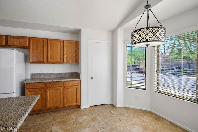 7755 Pacific Rim Ct, Las Vegas, NV 89139 - kitchen featuring freestanding refrigerator, brown cabinets, baseboards, and pendant lighting