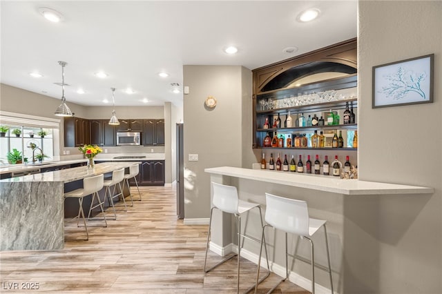 8100 Lake Hills Dr, Las Vegas, NV 89128 - bar with stainless steel microwave, a sink, light wood-style floors, hanging light fixtures, and recessed lighting