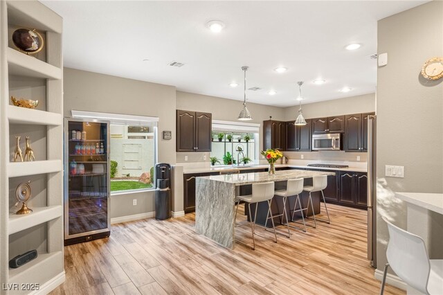 8100 Lake Hills Dr, Las Vegas, NV 89128 - kitchen featuring dark brown cabinets, a kitchen island, stainless steel appliances, a kitchen bar, and wine cooler