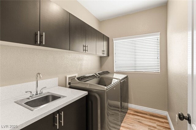 8100 Lake Hills Dr, Las Vegas, NV 89128 - washroom with separate washer and dryer, cabinet space, light wood-style flooring, baseboards, and a textured wall