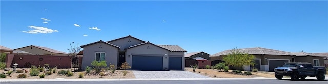 view of front of property featuring an attached garage, decorative driveway, stucco siding, and fence