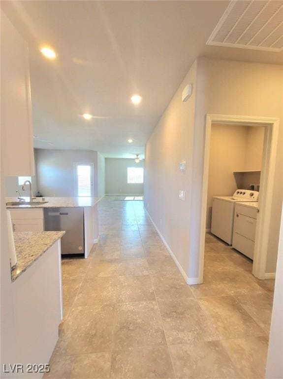 hall featuring independent washer and dryer, a sink, recessed lighting, and baseboards