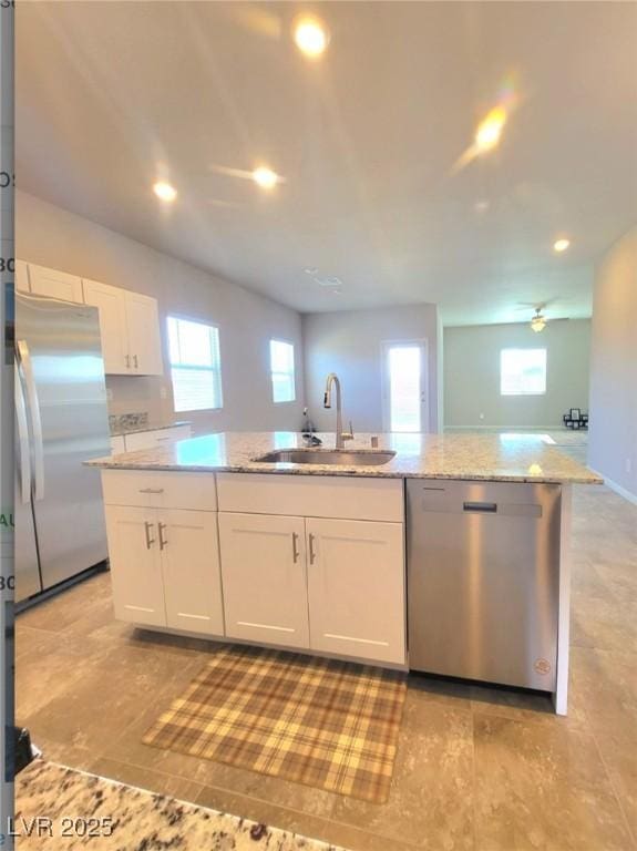 kitchen featuring stainless steel appliances, a sink, white cabinets, light stone counters, and recessed lighting