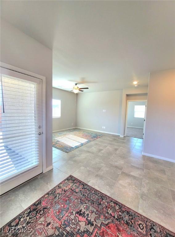 unfurnished room featuring ceiling fan and baseboards