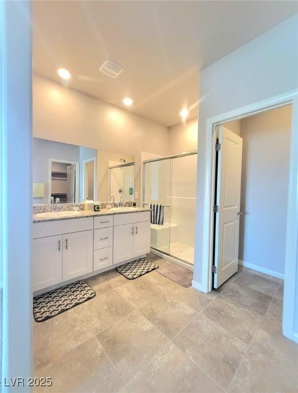 full bath featuring a shower stall, double vanity, baseboards, and recessed lighting