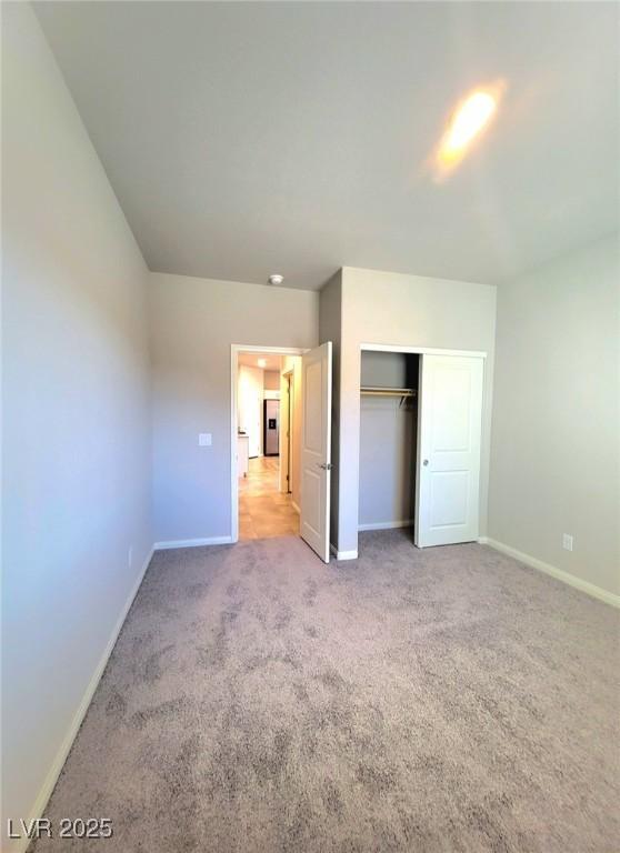 unfurnished bedroom featuring baseboards, carpet, and a closet