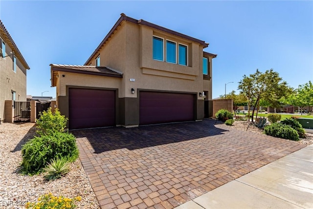 view of front of home with stucco siding, decorative driveway, and a garage