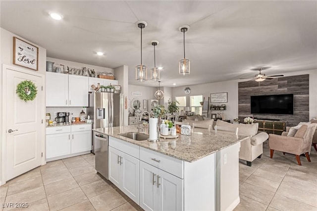 kitchen featuring a sink, open floor plan, light tile patterned floors, appliances with stainless steel finishes, and white cabinets