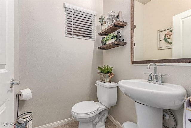 bathroom featuring toilet and baseboards