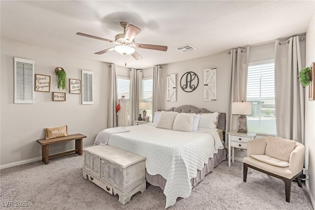 bedroom featuring multiple windows, light carpet, a ceiling fan, and baseboards