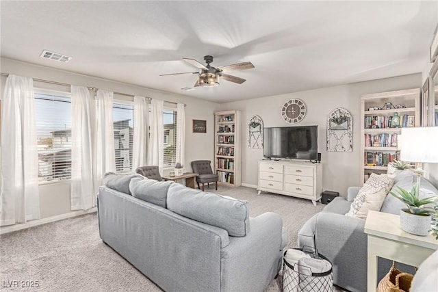 living area featuring light colored carpet, a ceiling fan, and baseboards