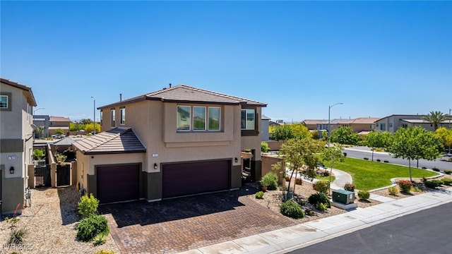 view of front of home featuring stucco siding, a garage, a tiled roof, decorative driveway, and a residential view