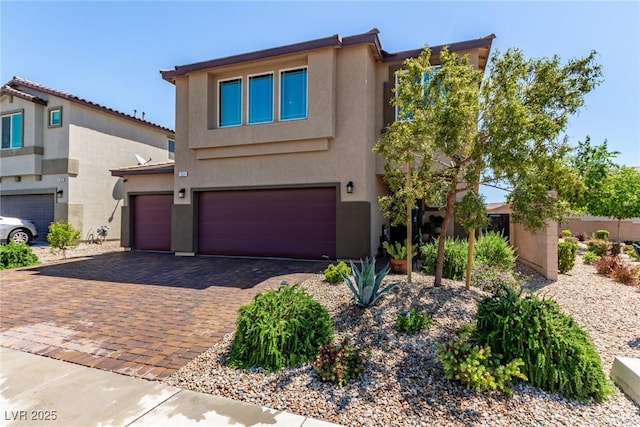 view of front of home featuring stucco siding, decorative driveway, and an attached garage
