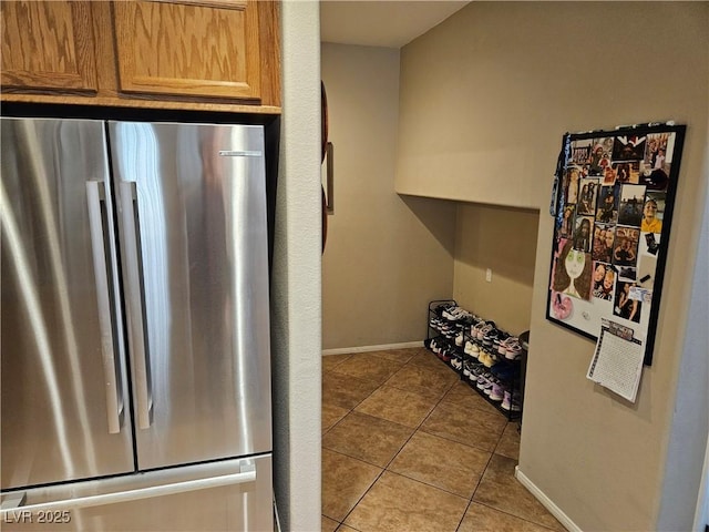 kitchen with freestanding refrigerator, light tile patterned flooring, and baseboards