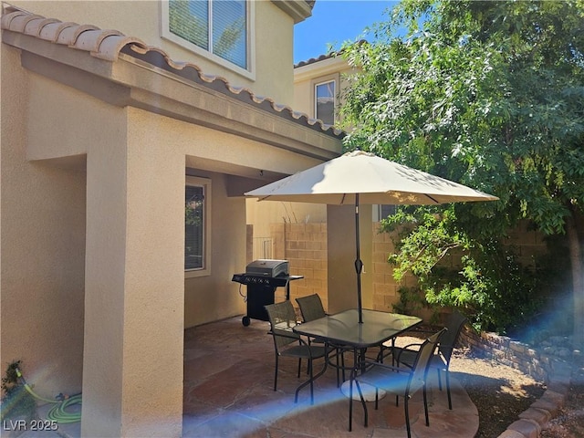view of patio featuring area for grilling, fence, and outdoor dining space