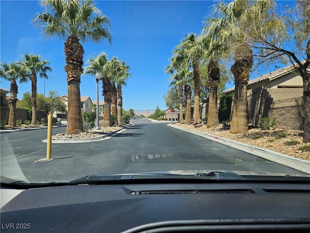 view of asphalt road featuring traffic signs and curbs
