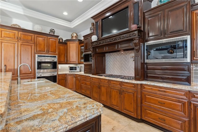 kitchen with appliances with stainless steel finishes, a sink, decorative backsplash, light stone countertops, and ornamental molding