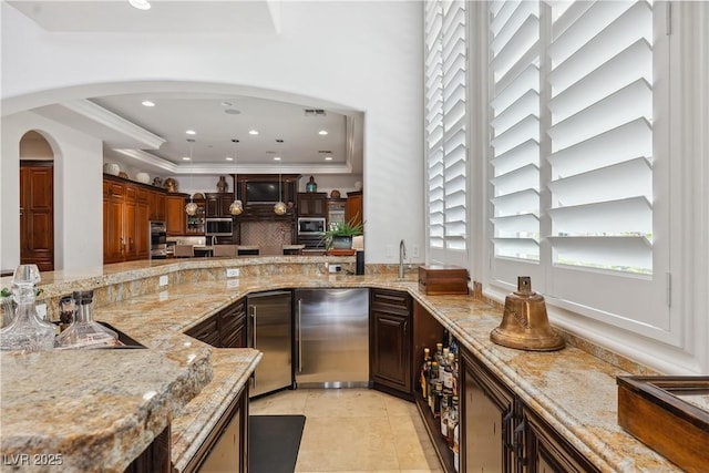 bar with healthy amount of natural light, high end fridge, crown molding, recessed lighting, and a raised ceiling
