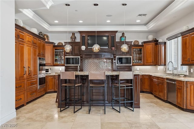kitchen featuring stainless steel appliances, a sink, a kitchen island with sink, a raised ceiling, and crown molding