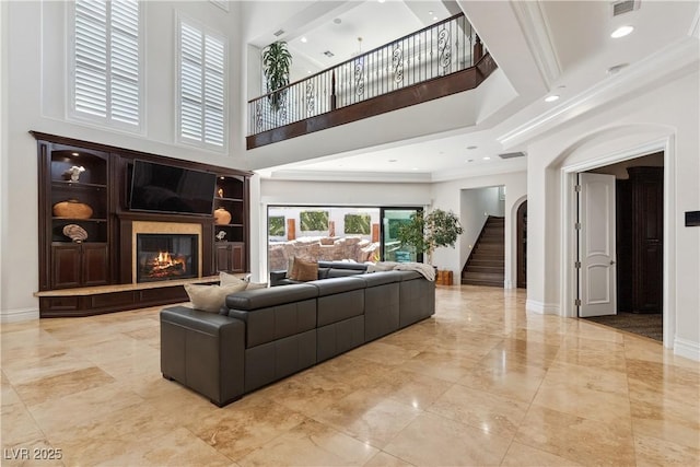 living area featuring a high ceiling, a fireplace, marble tiled flooring, baseboards, and stairway