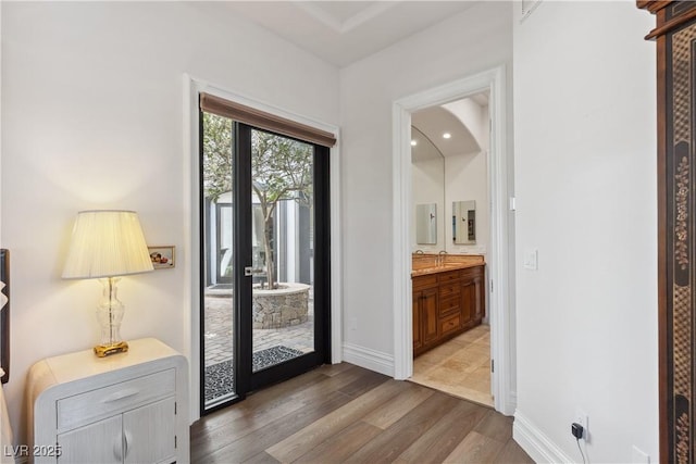 doorway to outside with wood finished floors, a sink, and baseboards