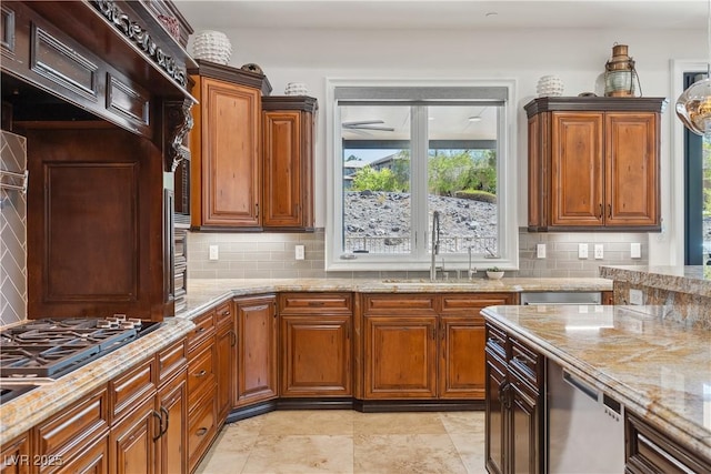 kitchen featuring tasteful backsplash, light stone countertops, a sink, gas cooktop, and brown cabinetry