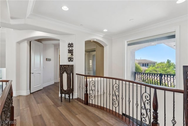 corridor with wood finished floors, arched walkways, baseboards, crown molding, and recessed lighting