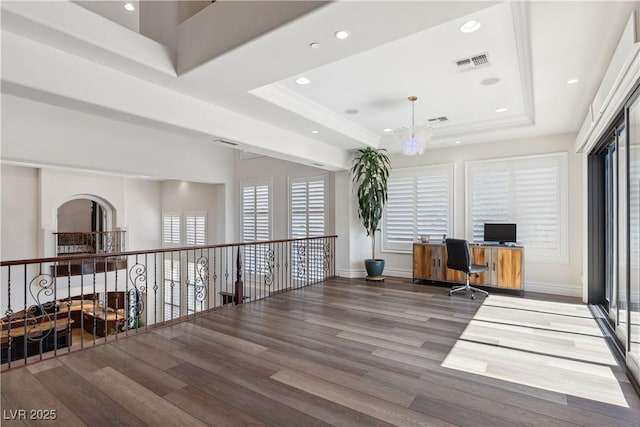 unfurnished office featuring a raised ceiling, wood finished floors, recessed lighting, a chandelier, and baseboards