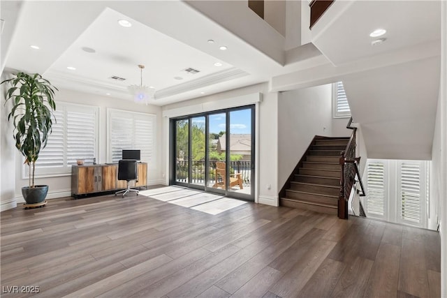 unfurnished living room featuring wood finished floors, a desk, a tray ceiling, and recessed lighting