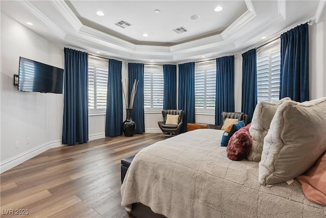 bedroom with a tray ceiling, wood finished floors, ornamental molding, baseboards, and recessed lighting