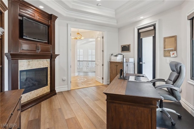 office space featuring a raised ceiling, light wood-style flooring, ornamental molding, a chandelier, and recessed lighting