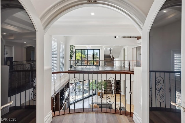 hallway featuring wood finished floors, recessed lighting, and arched walkways