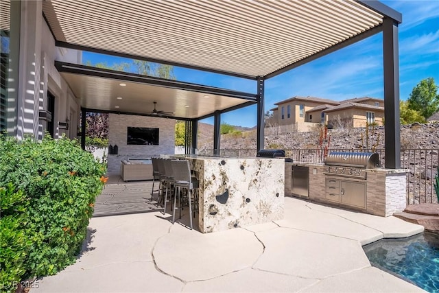 view of patio featuring exterior kitchen, a grill, fence, and ceiling fan