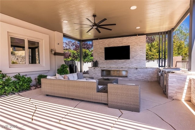 view of patio featuring an outdoor kitchen, an outdoor living space with a fireplace, and ceiling fan