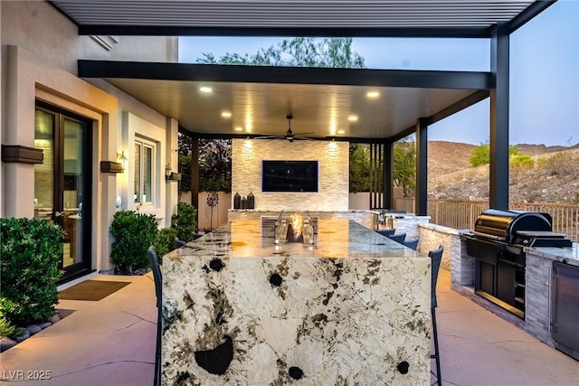 view of patio / terrace with an outdoor kitchen, a fenced backyard, a ceiling fan, and grilling area