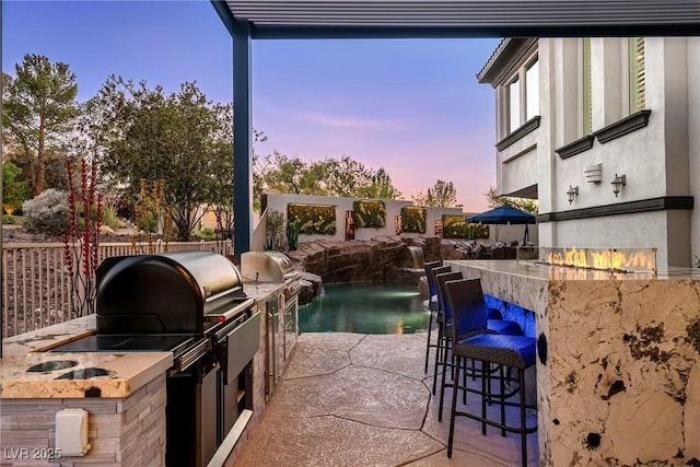 view of swimming pool featuring an outdoor kitchen, a grill, and a patio area