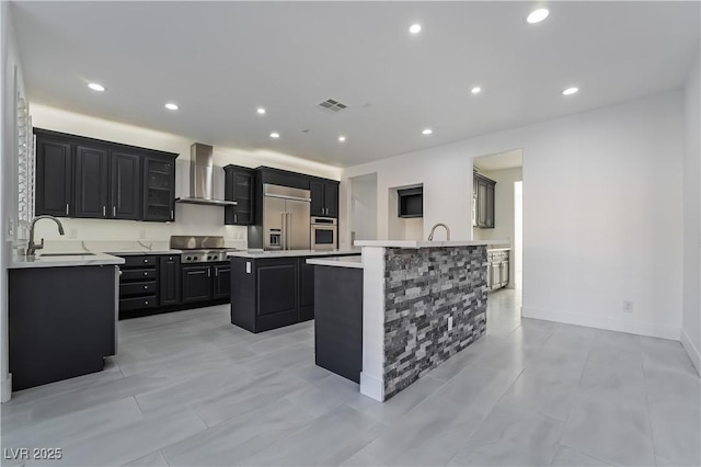 1316 Eagle Meadow Ct, Las Vegas, NV 89123 - kitchen featuring appliances with stainless steel finishes, wall chimney range hood, a sink, dark cabinetry, and a kitchen island