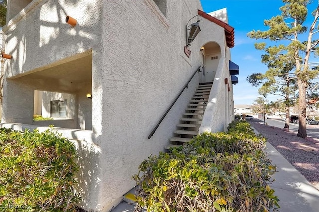 view of side of home featuring stairway and stucco siding