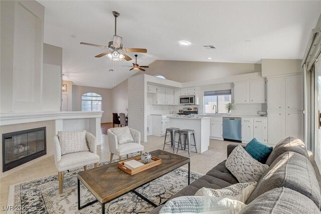 832 Seco Verde Ave, Henderson, NV 89015 - living area with vaulted ceiling, light tile patterned flooring, a ceiling fan, and a tile fireplace