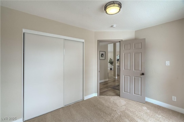unfurnished bedroom featuring carpet, a closet, and baseboards