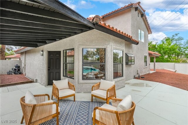 back of house featuring a patio, stucco siding, fence, and a tiled roof