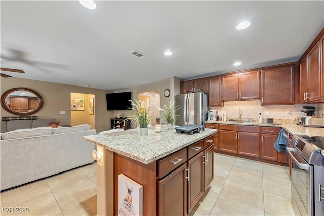 3966 E Garfield Dr, Pahrump, NV 89061 - kitchen with appliances with stainless steel finishes, open floor plan, light stone counters, light tile patterned floors, and a ceiling fan