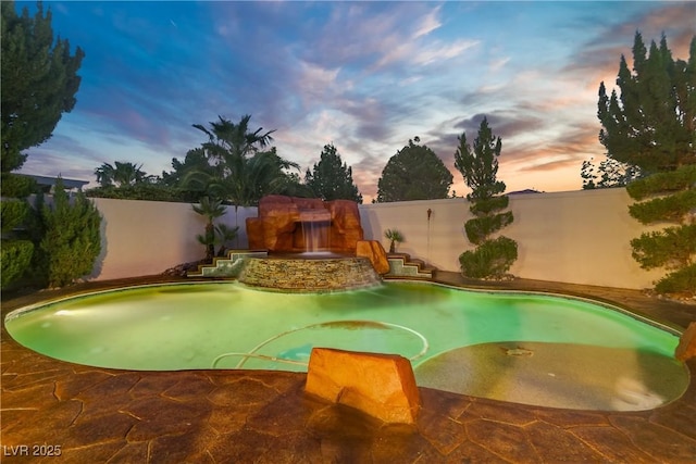 pool at dusk featuring a fenced backyard
