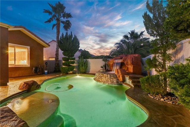 pool at dusk with a fenced backyard and a patio area